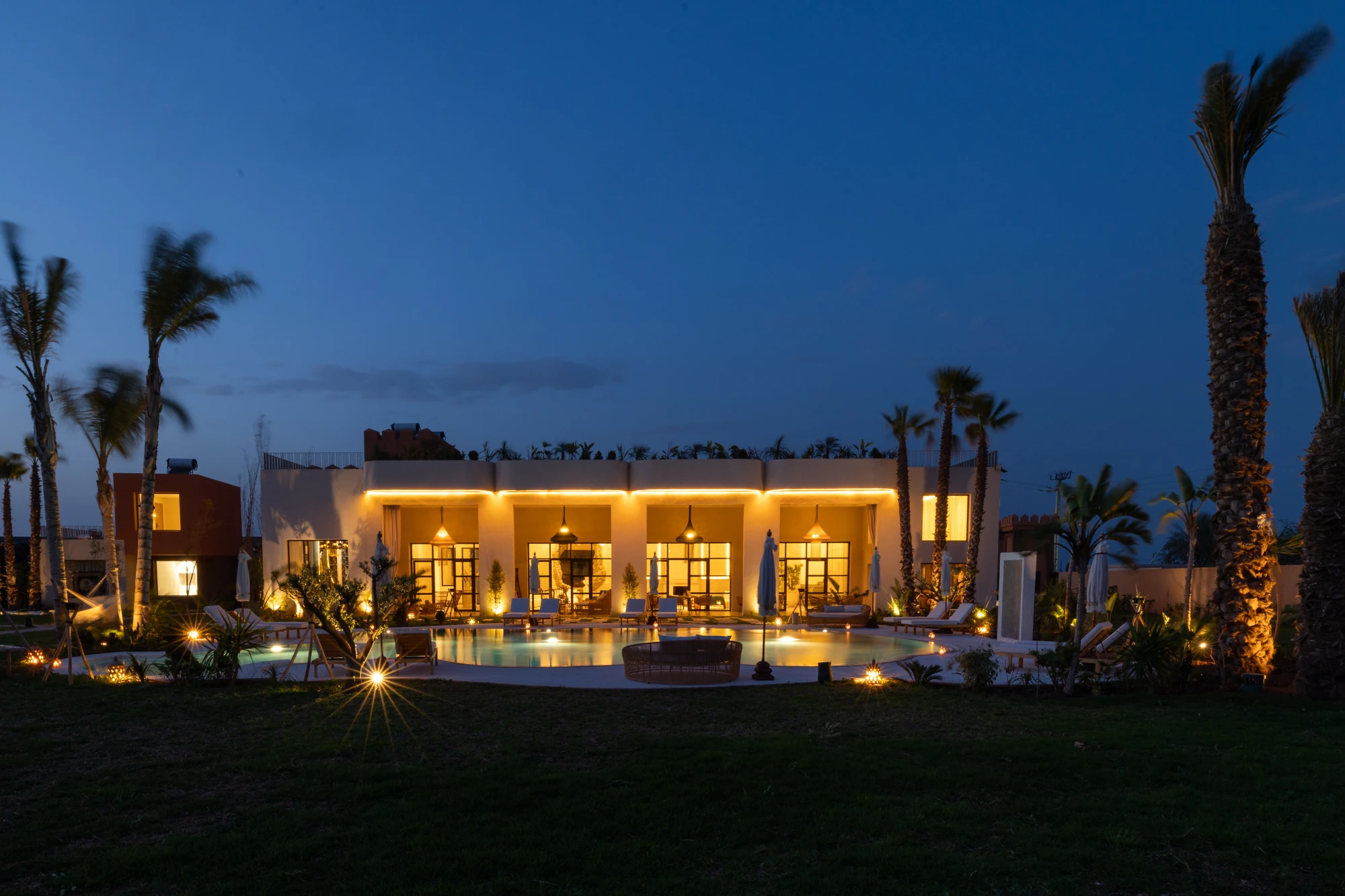 Façade de Yin Hotel éclairée le soir, entourée de palmiers