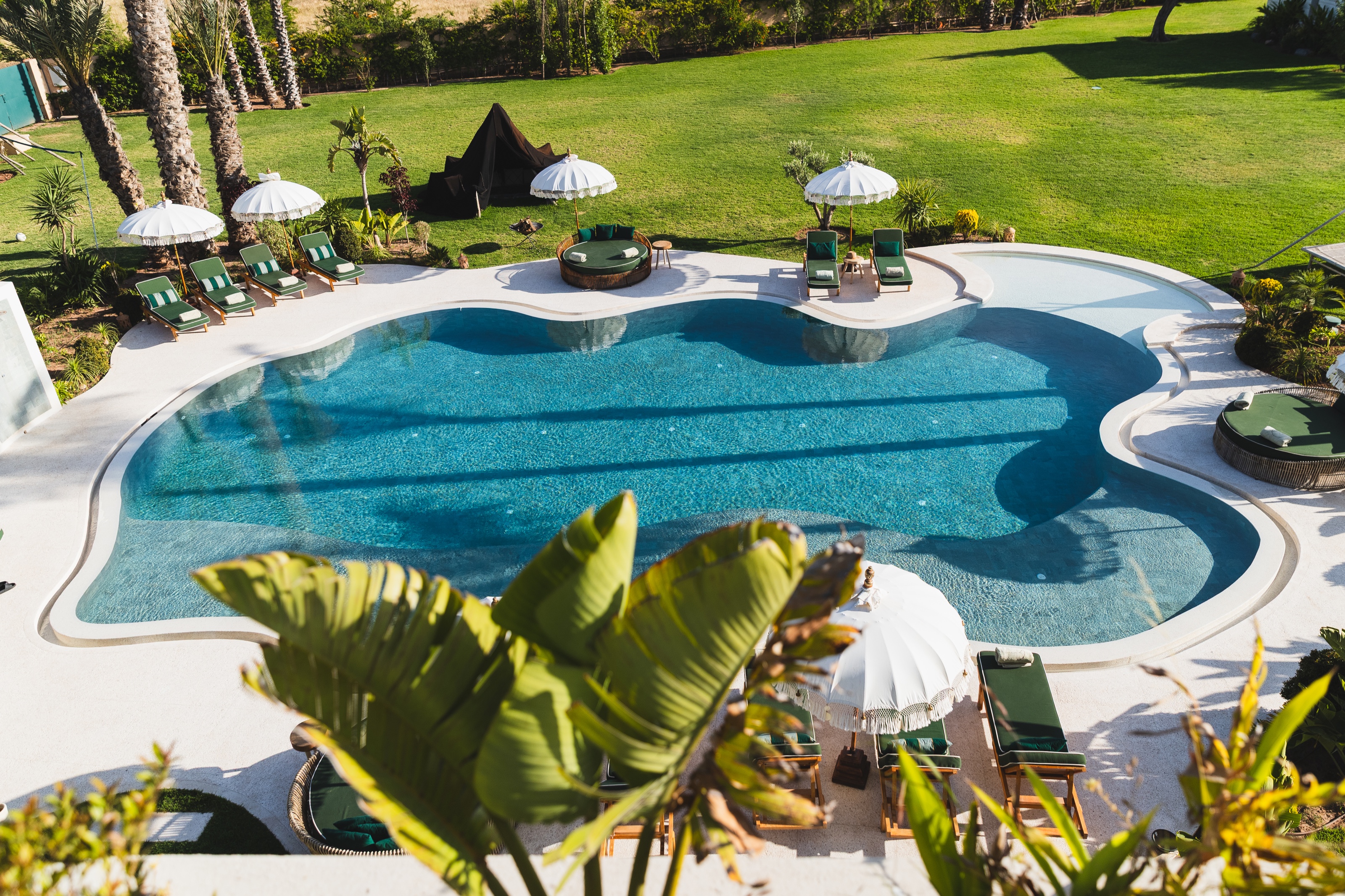 Piscine aux courbes arrondies entourée des jardins de Yin Hotel