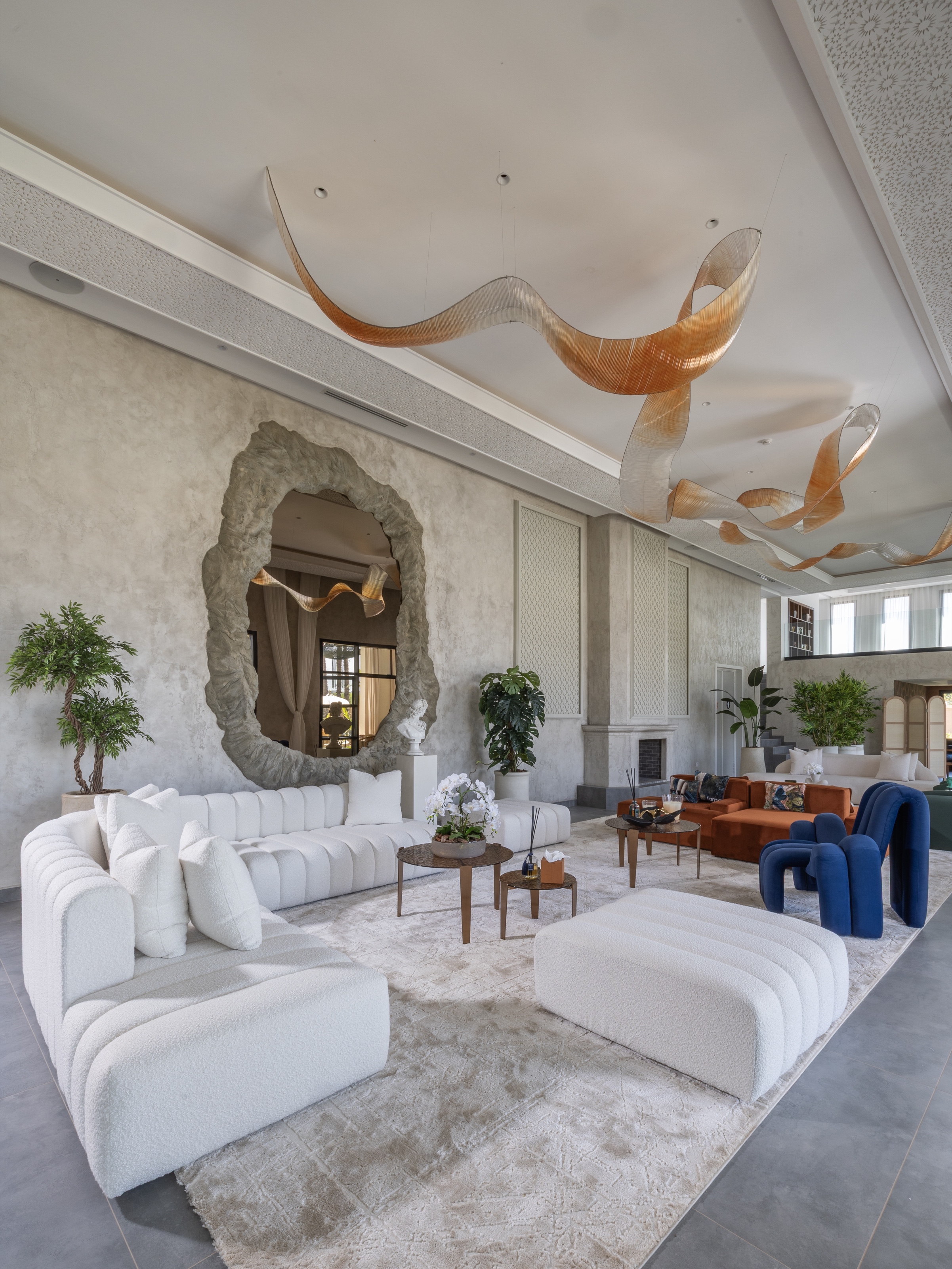 Salon lumineux de Yin Hotel avec canapés blancs, fauteuils bleus et miroir sculpté