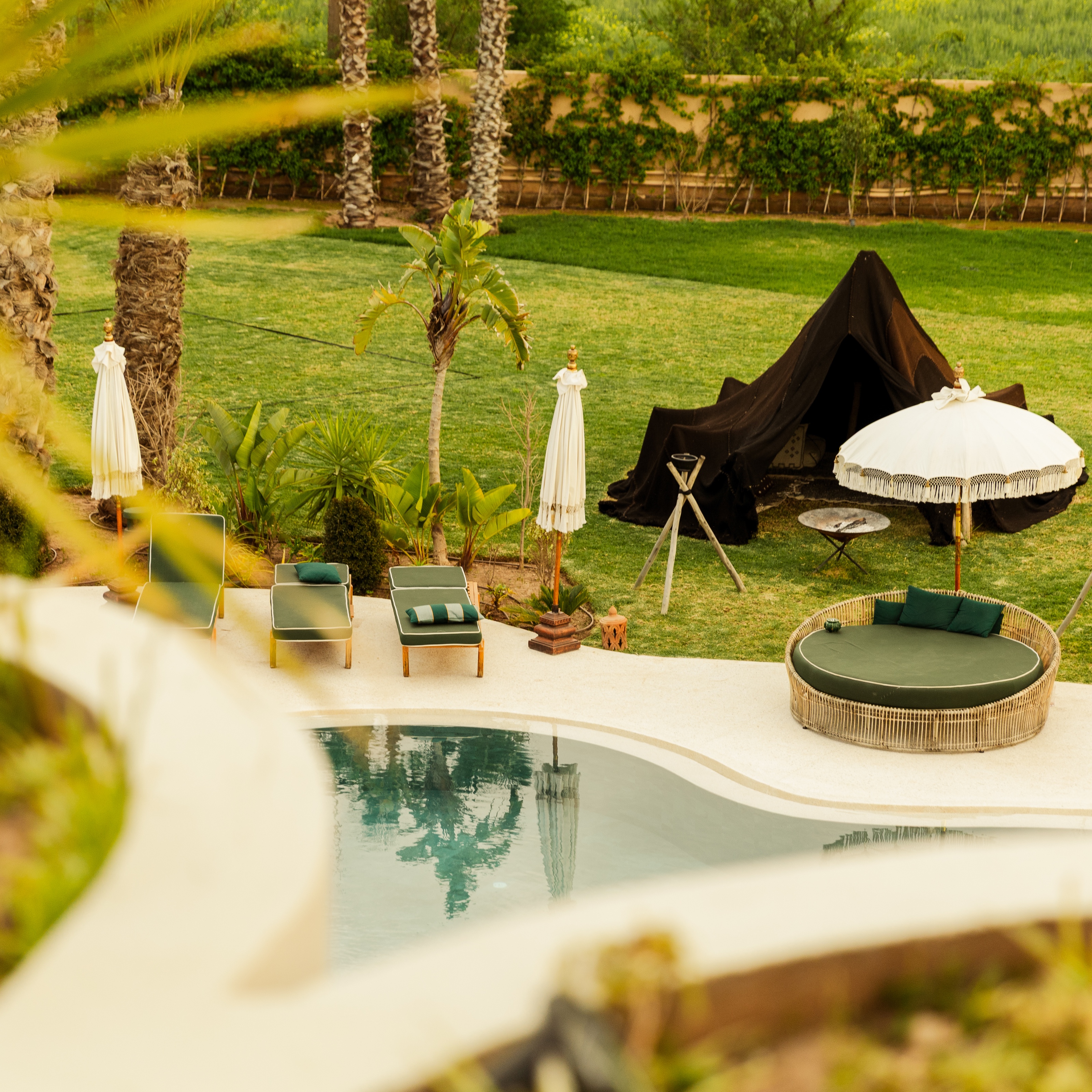 Espace détente au bord de la piscine Yin, avec parasols et coussins verts